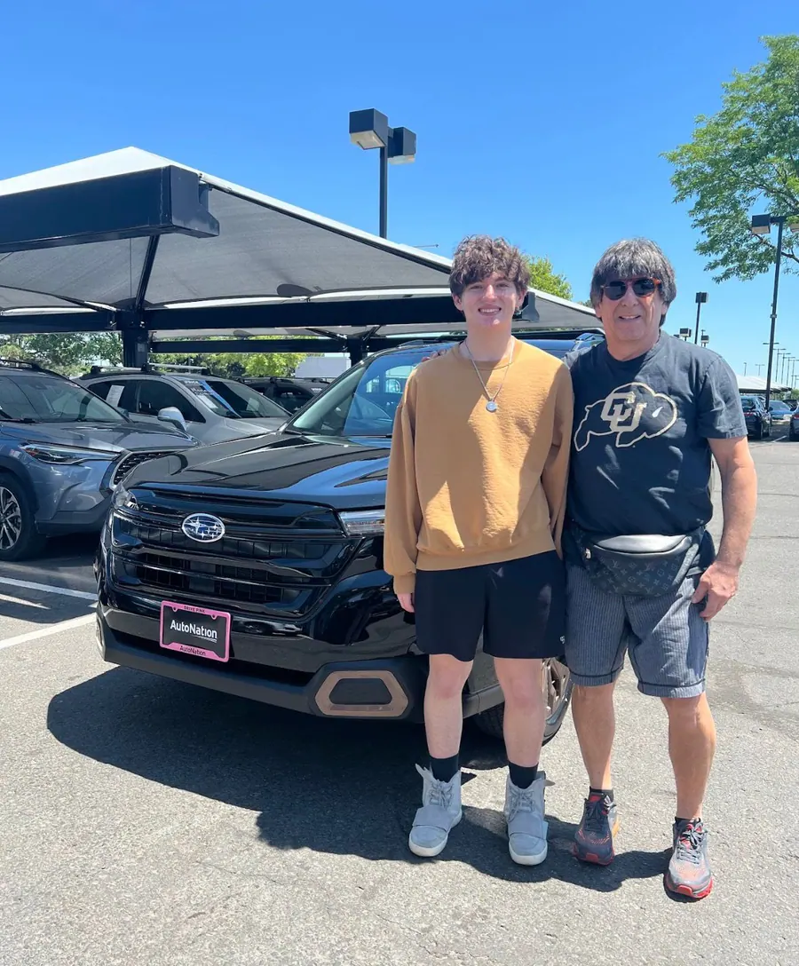 Father and son taking delivery of a black Subaru Forester