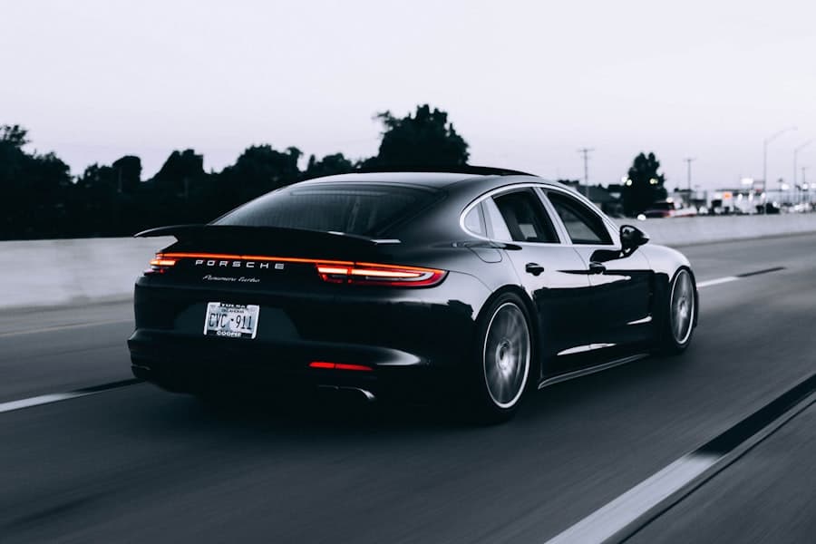 Black Porsche Panamera driving on a highway at dusk