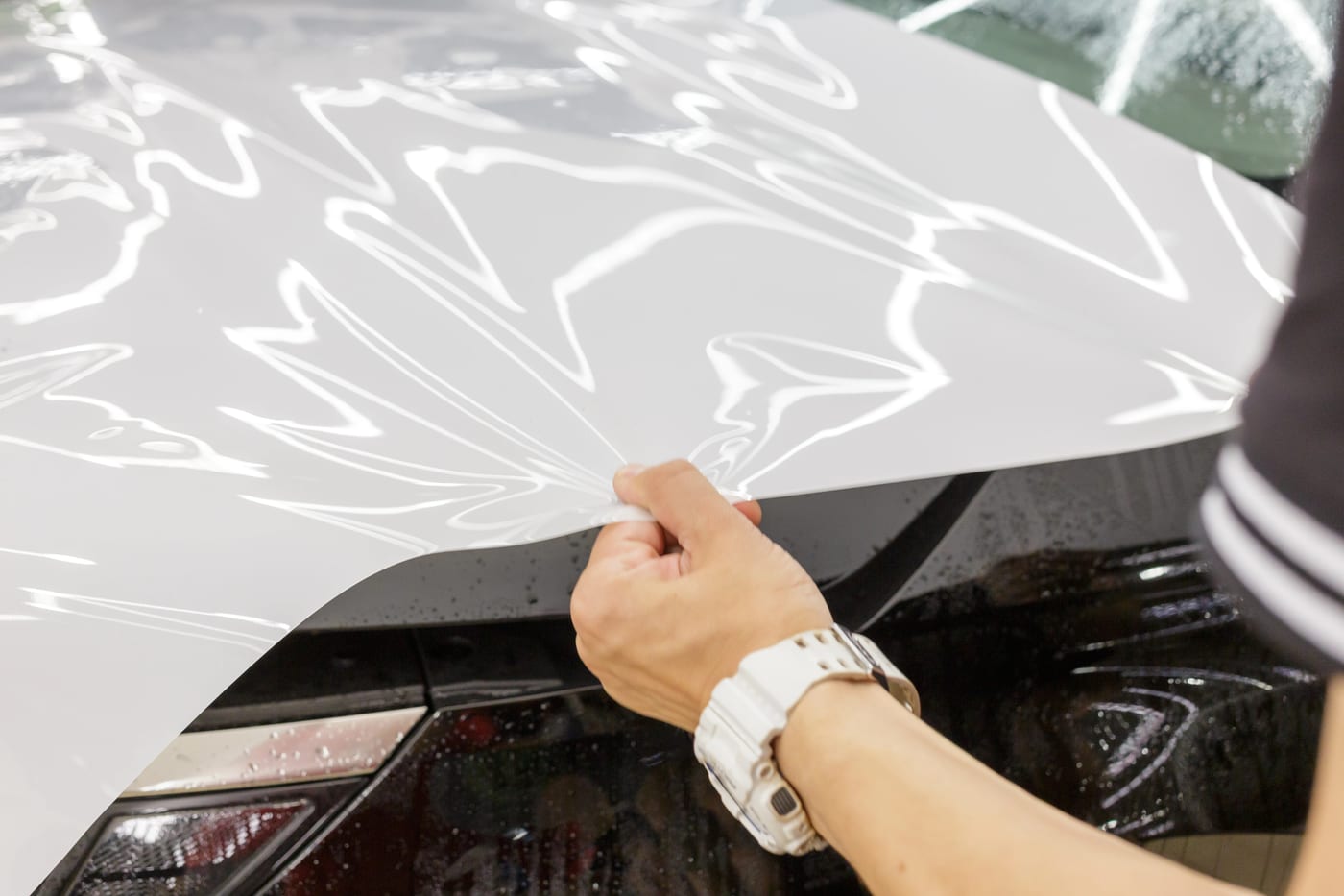 A technician applying paint protection film to a car's hood